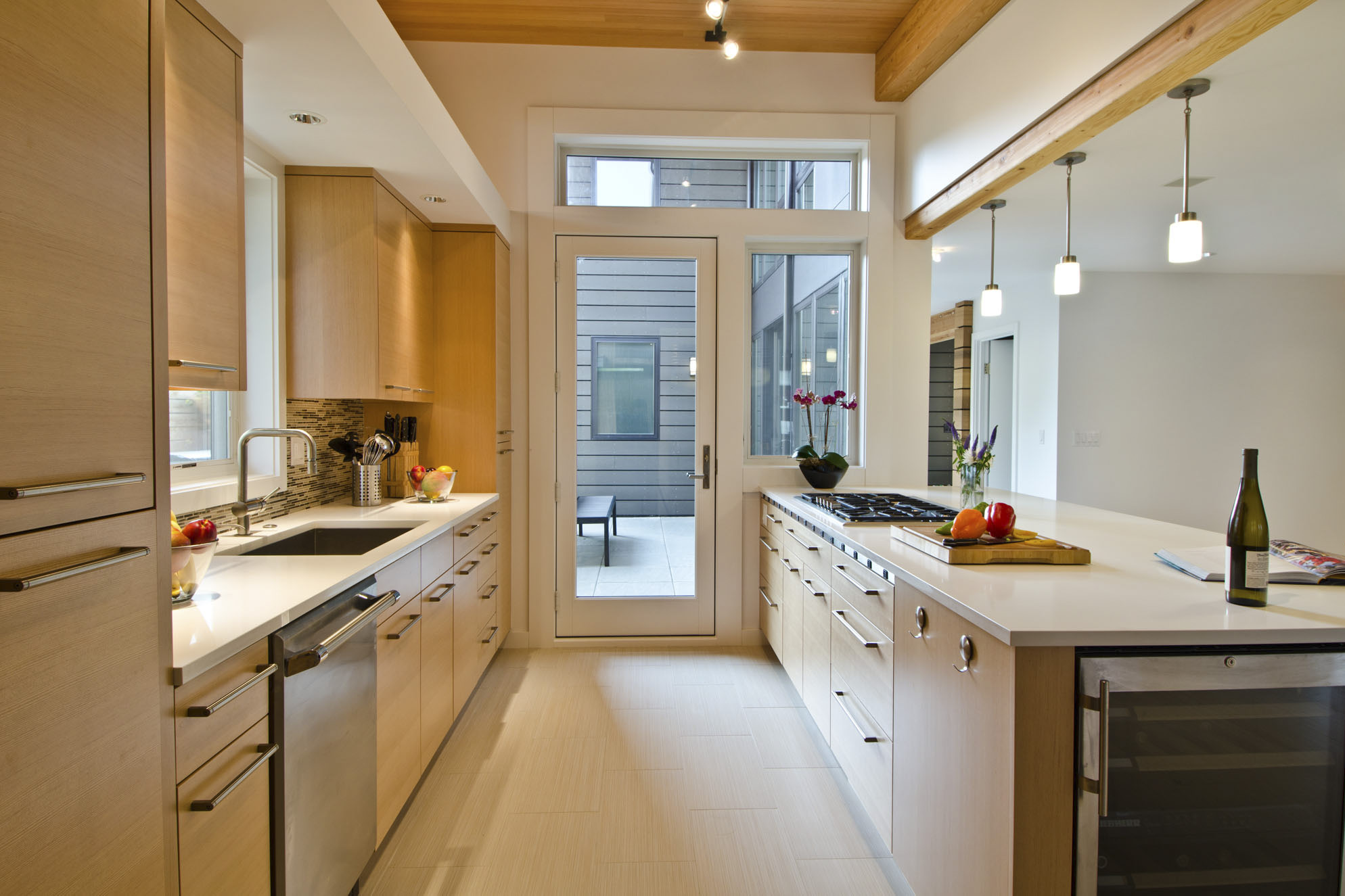First slide - Modern home galley kitchen with indoor outdoor space and bar seating
